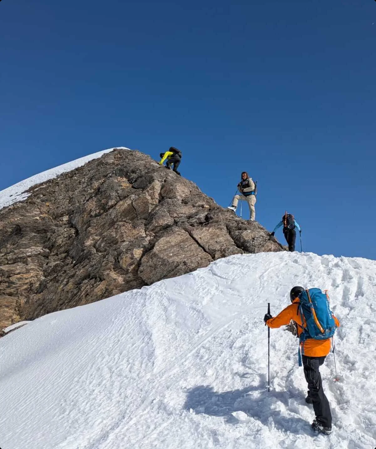 Vier Personen steigen mit Winterausrüstung einen verschneiten Berggipfel bei blauem Himmel hinauf. | © DAV Dortmund