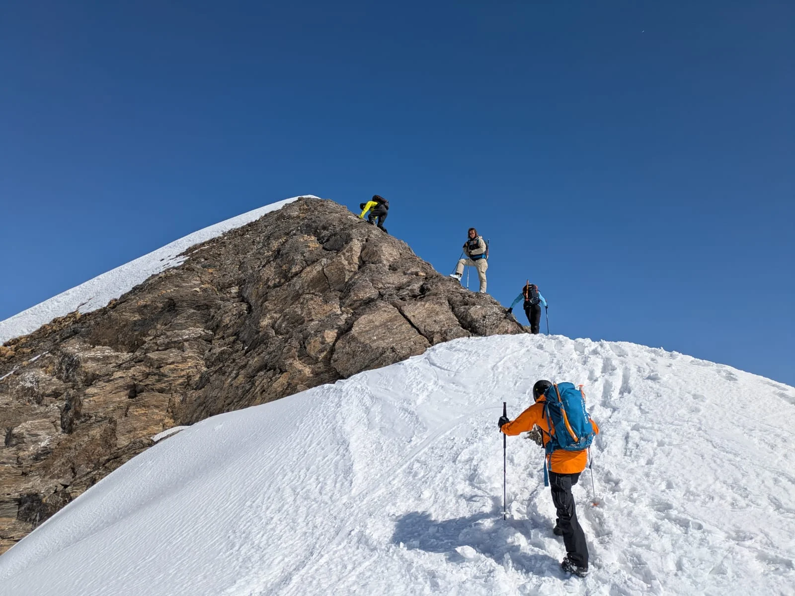 Vier Personen steigen mit Winterausrüstung einen verschneiten Berggipfel bei blauem Himmel hinauf. | © DAV Dortmund