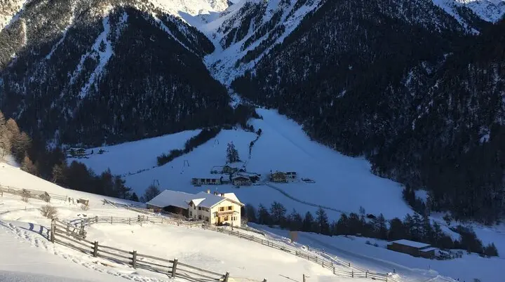 Ein verschneites Tal mit einem Bauernhof im Vordergrund, umgeben von schneebedeckten Bergen. | © DAV Dortmund