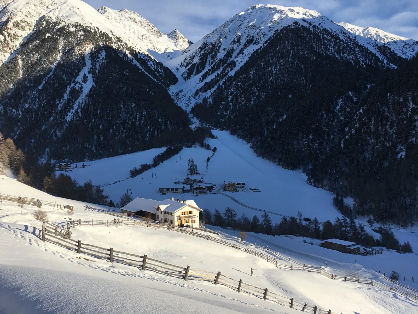 Ein verschneites Tal mit einem Bauernhof im Vordergrund, umgeben von schneebedeckten Bergen. | © DAV Dortmund