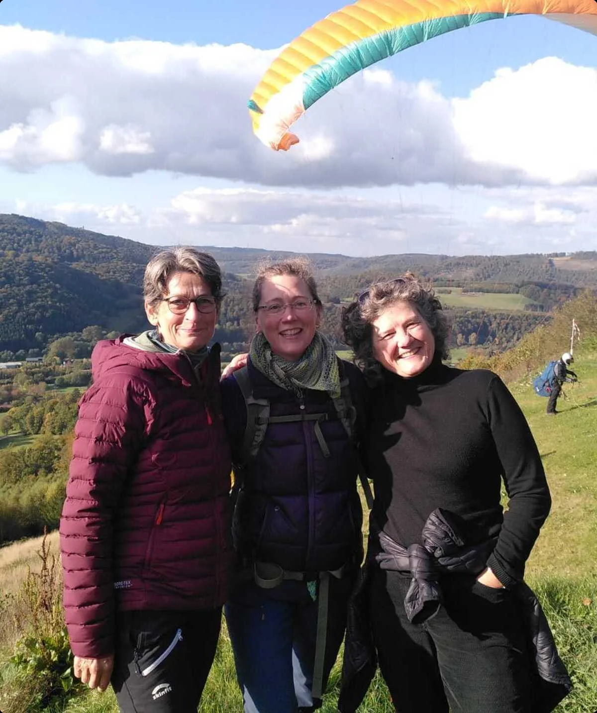 Drei Frauen stehen vor einem bunten Gleitschirm mit Blick ins weite Tal. | © DAV Dortmund