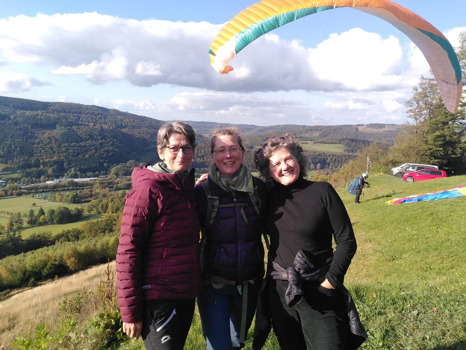 Drei Frauen stehen vor einem bunten Gleitschirm mit Blick ins weite Tal. | © DAV Dortmund