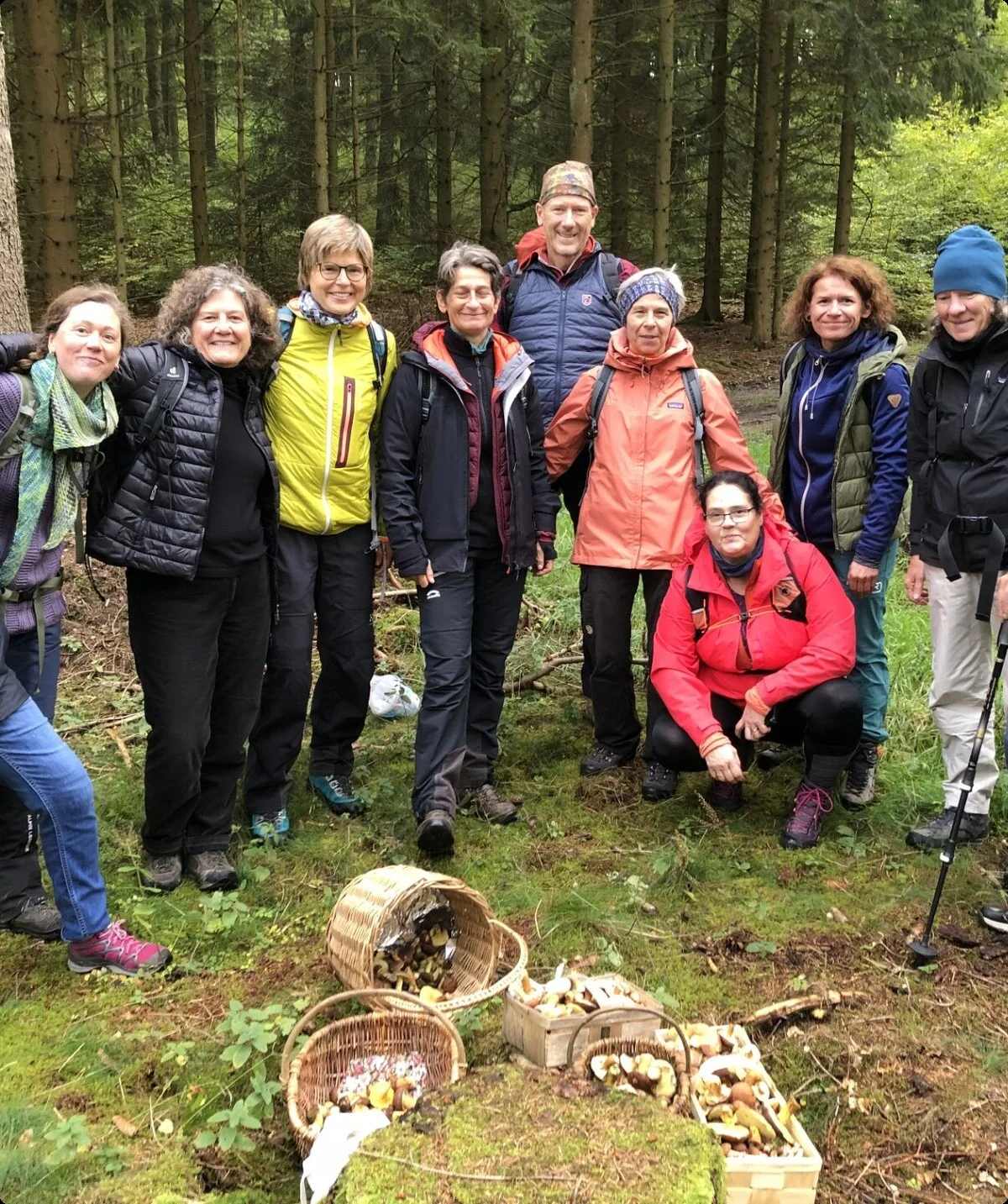Gruppe steht im Wald hinter mehreren vollen Pilzkörben und lächelt in die Kamera. | © DAV Dortmund