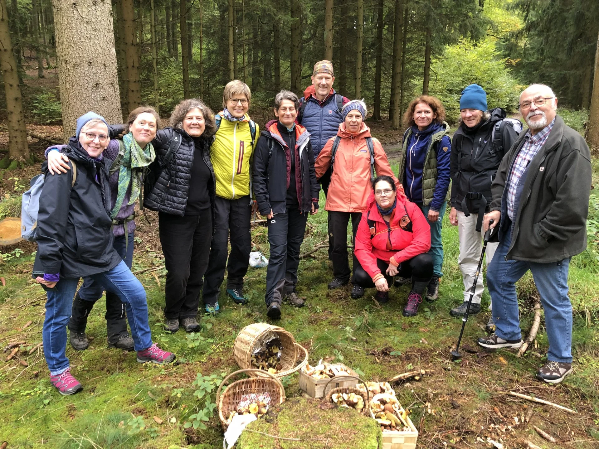 Gruppe steht im Wald hinter mehreren vollen Pilzkörben und lächelt in die Kamera. | © DAV Dortmund