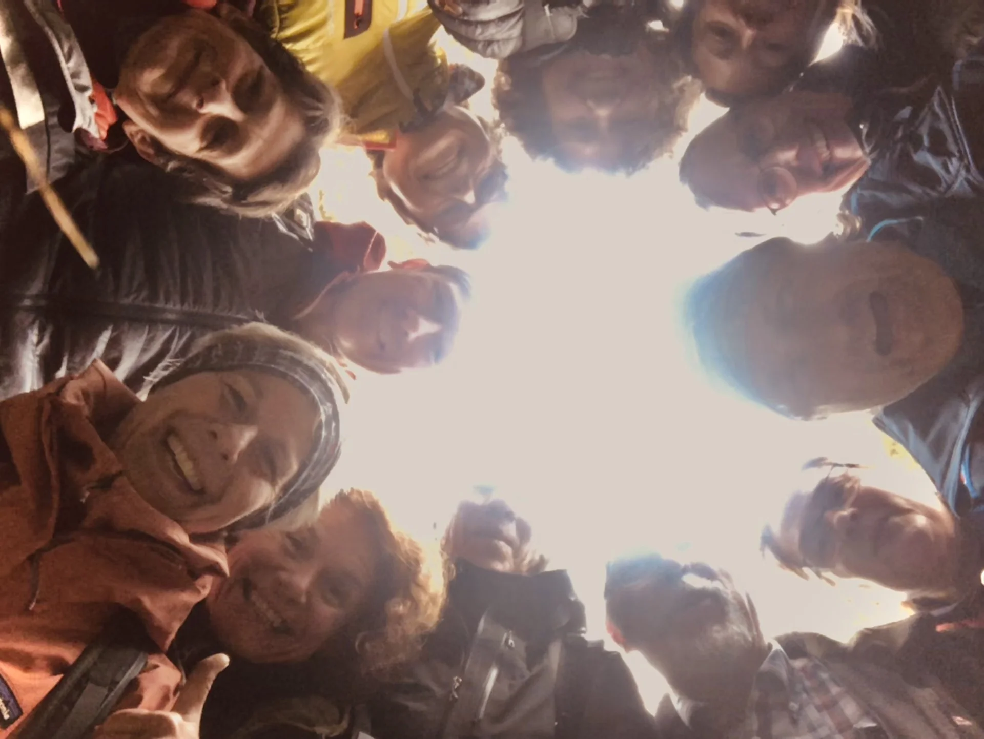 Gruppe von Menschen blickt im Kreis stehend nach unten in die Kamera und lacht. | © DAV Dortmund