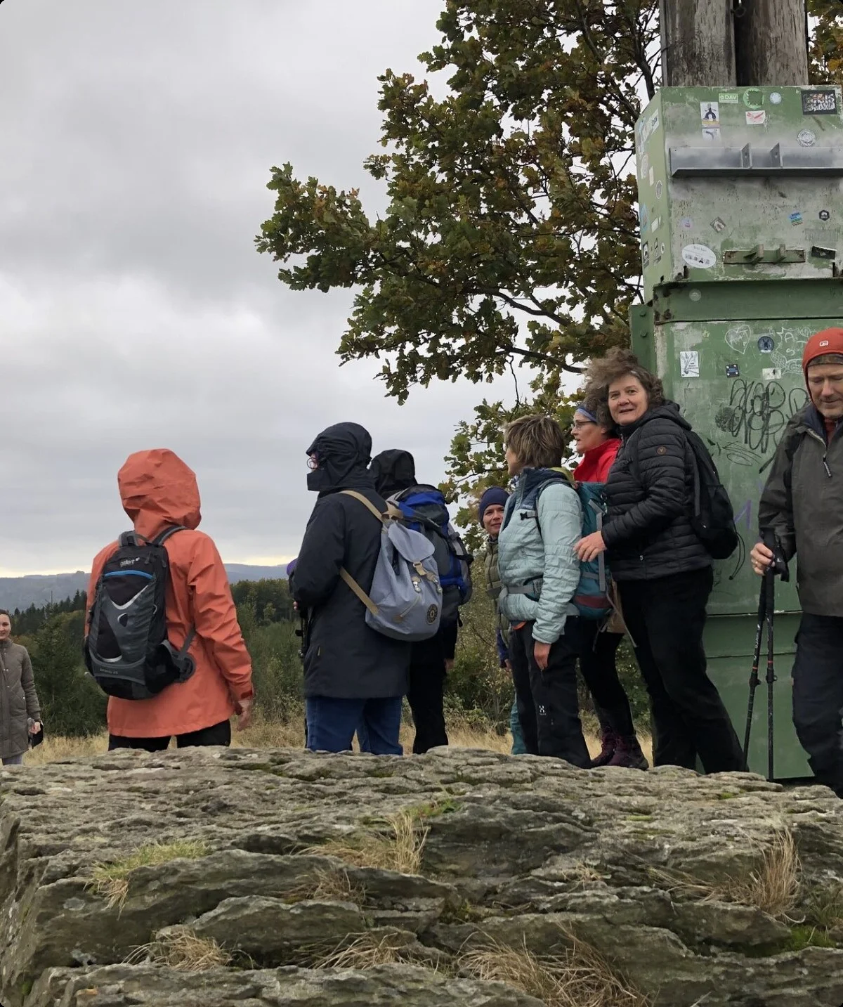 Mehrere Personen stehen lachend an einem Gipfel mit Metalltafel und weitem Ausblick. | © DAV Dortmund