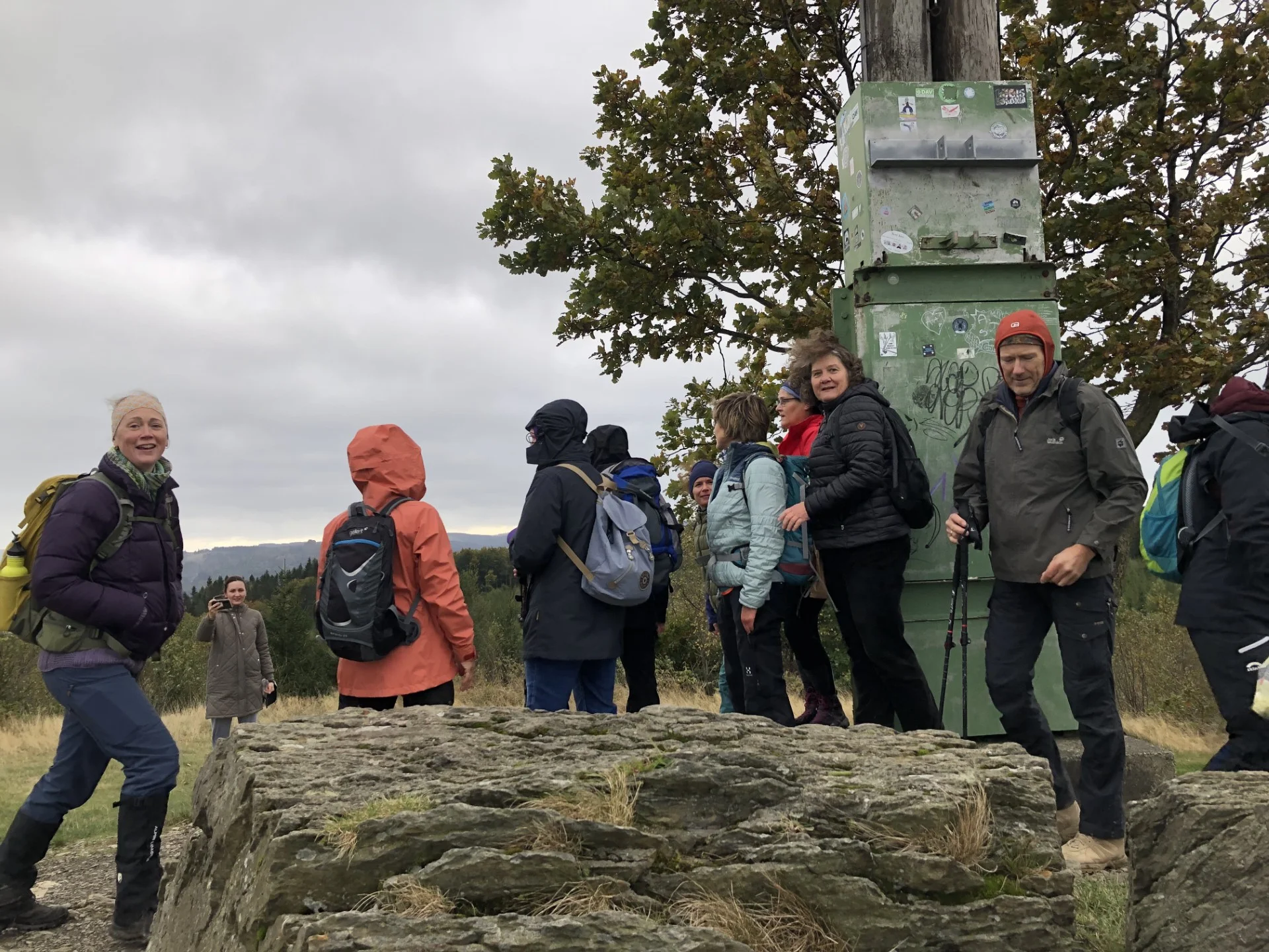Mehrere Personen stehen lachend an einem Gipfel mit Metalltafel und weitem Ausblick. | © DAV Dortmund
