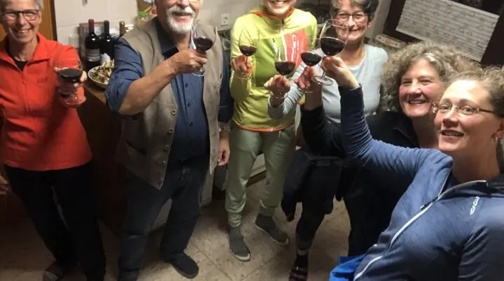 Sechs Personen stoßen mit Rotweingläsern in einer gemütlichen Küche an. | © DAV Dortmund