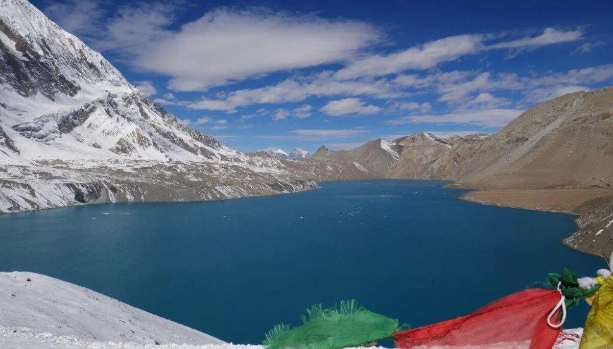 Tiefblauer Bergsee mit Schnee und bunten Gebetsfahnen im Vordergrund. | © DAV Dortmund
