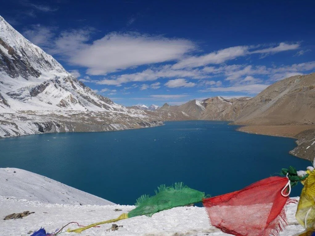 Tiefblauer Bergsee mit Schnee und bunten Gebetsfahnen im Vordergrund. | © DAV Dortmund