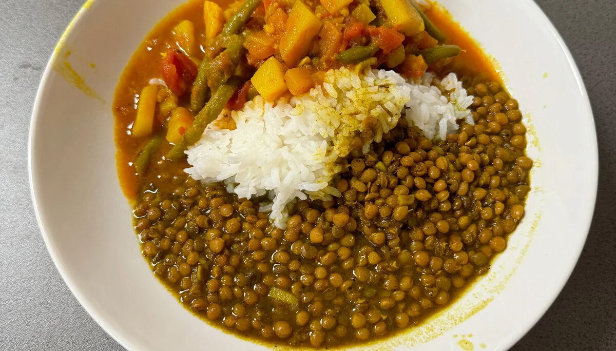Ein Teller mit Linsen, Reis und buntem Gemüse in Soße auf einem Tisch. | © DAV Dortmund