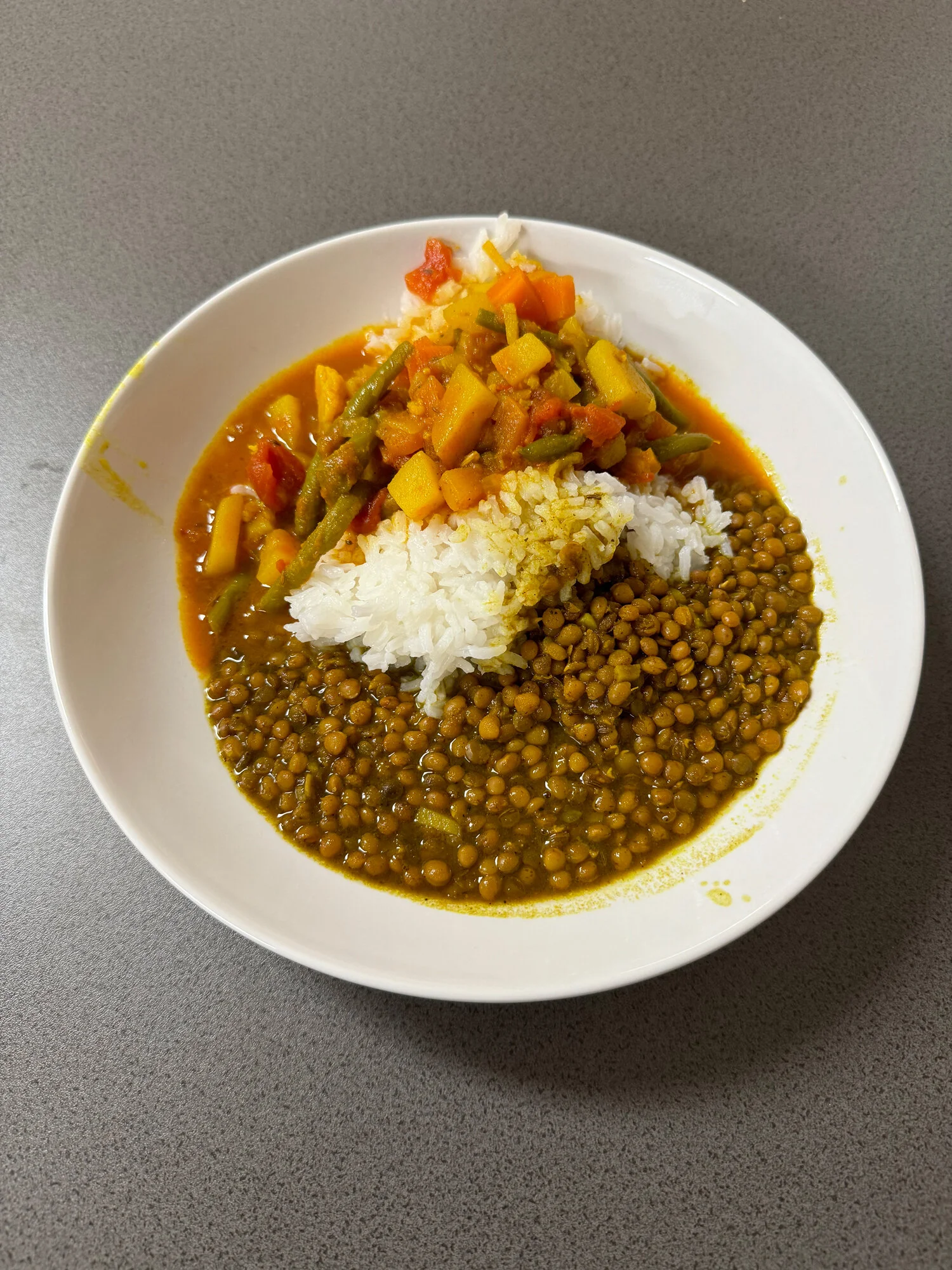 Ein Teller mit Linsen, Reis und buntem Gemüse in Soße auf einem Tisch. | © DAV Dortmund