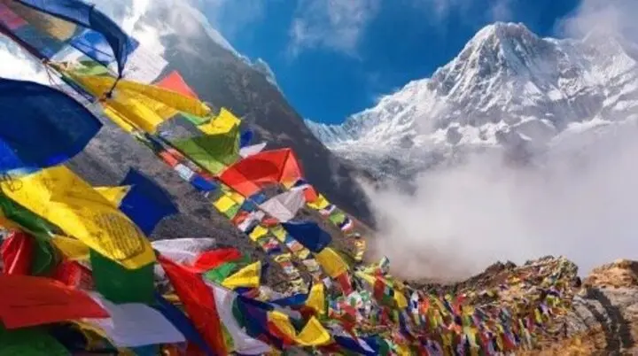 Bunte tibetische Gebetsfahnen flattern im Wind vor einer beeindruckenden Berglandschaft mit Schnee und Nebel | © DAV Dortmund