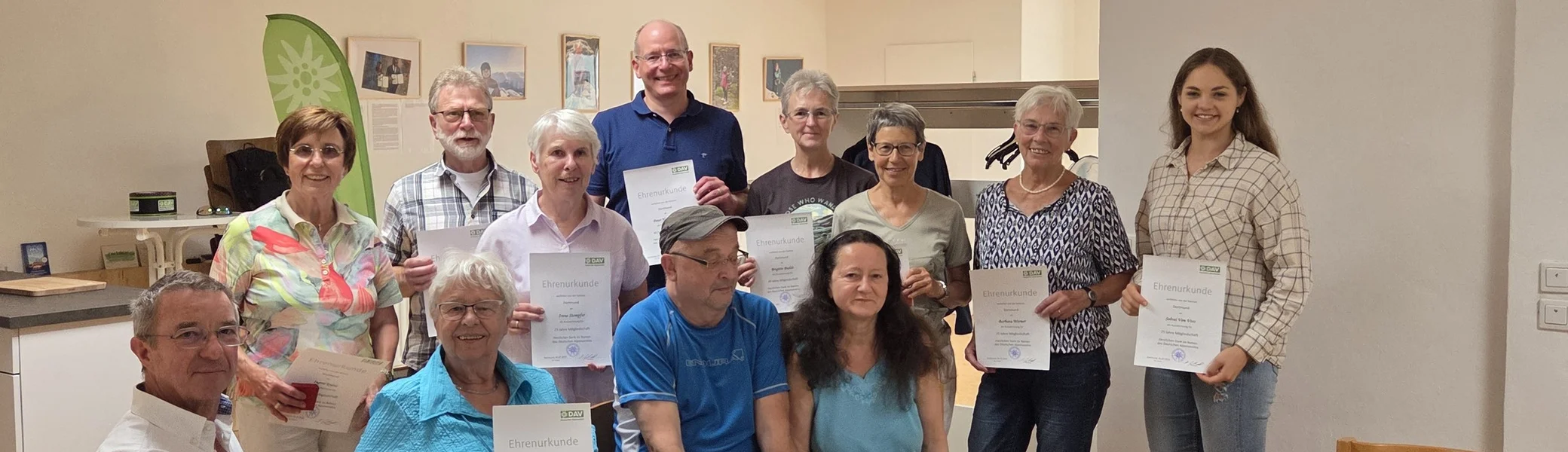 Gruppenbild mit allen geehrten Mitgliedern der DAV Sektion Dortmund, alle halten ihre Urkunden in den Händen und lächeln. | © DAV Dortmund