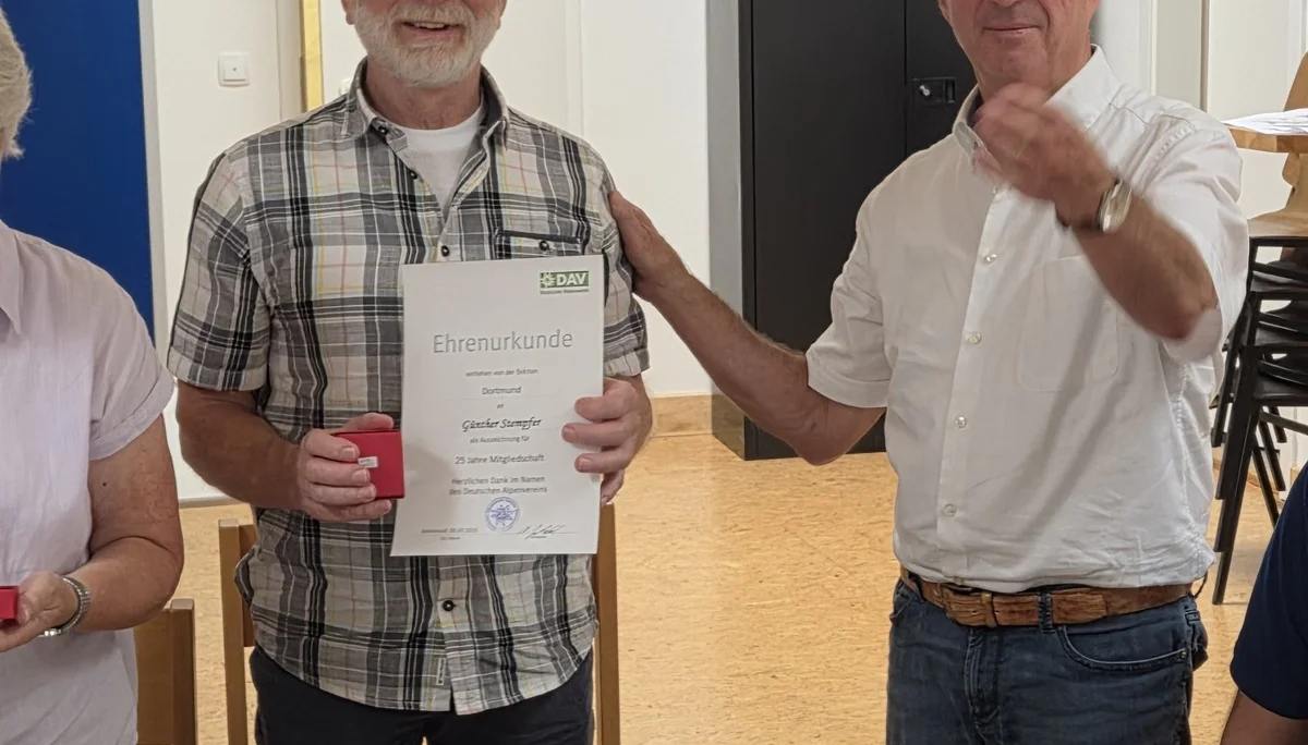 Günter erhält eine Ehrenurkunde für 25 Jahre Mitgliedschaft bei der DAV Sektion Dortmund. Er steht mit einem weiteren Mitglied, beide lächeln in die Kamera. | © DAV Dortmund