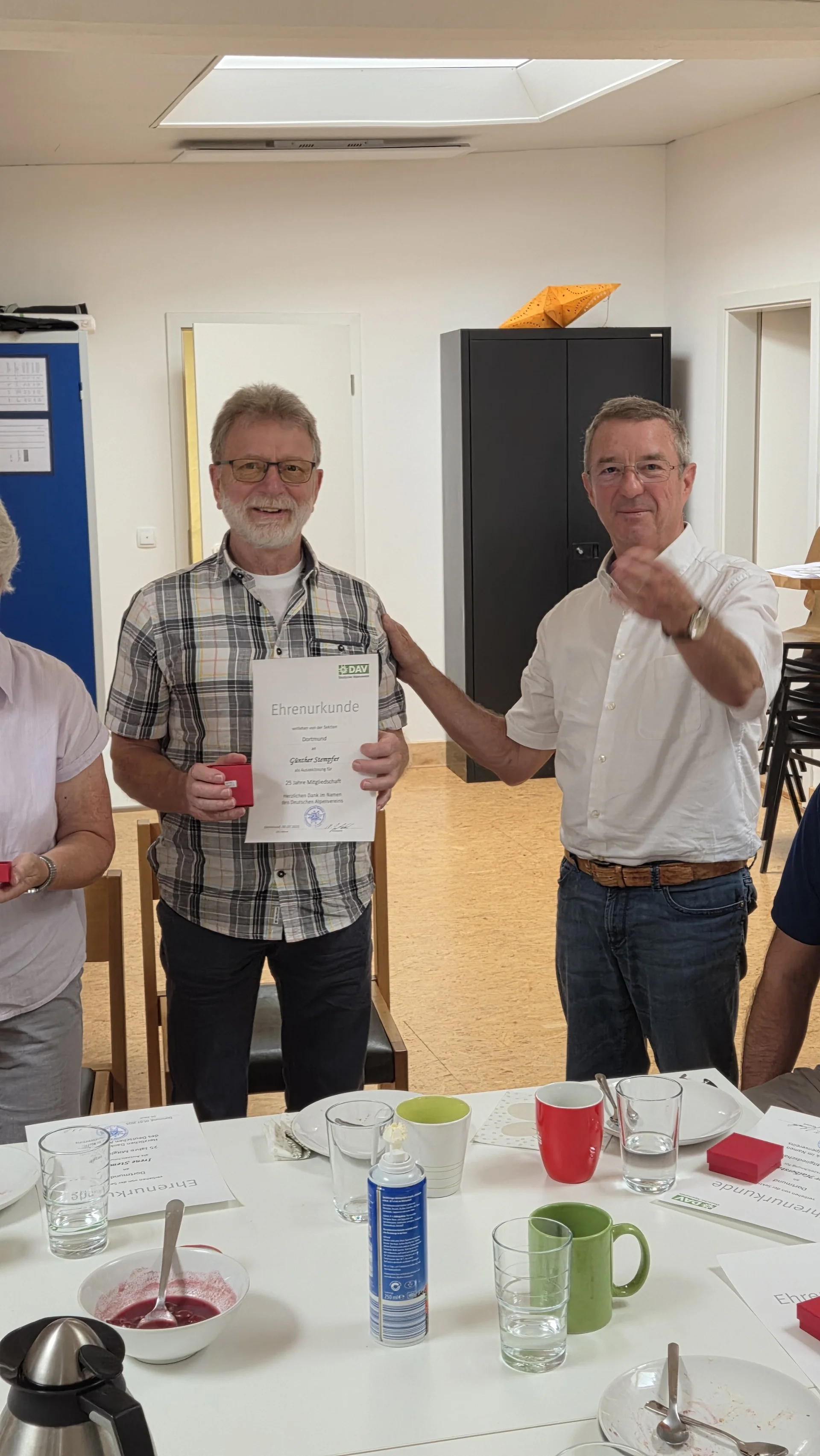 Günter erhält eine Ehrenurkunde für 25 Jahre Mitgliedschaft bei der DAV Sektion Dortmund. Er steht mit einem weiteren Mitglied, beide lächeln in die Kamera. | © DAV Dortmund