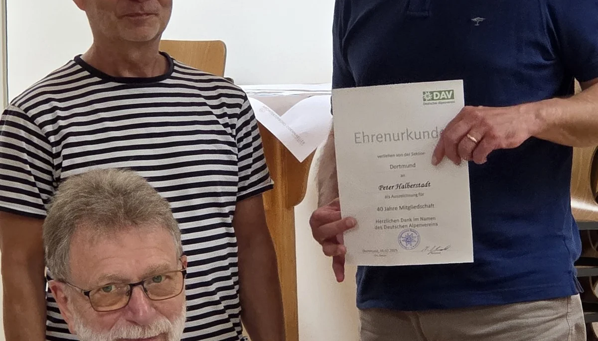 Peter bekommt eine Urkunde für 40 Jahre Mitgliedschaft bei der DAV Sektion Dortmund, daneben stehen Peter und ein weitere Mitglieder. | © DAV Dortmund