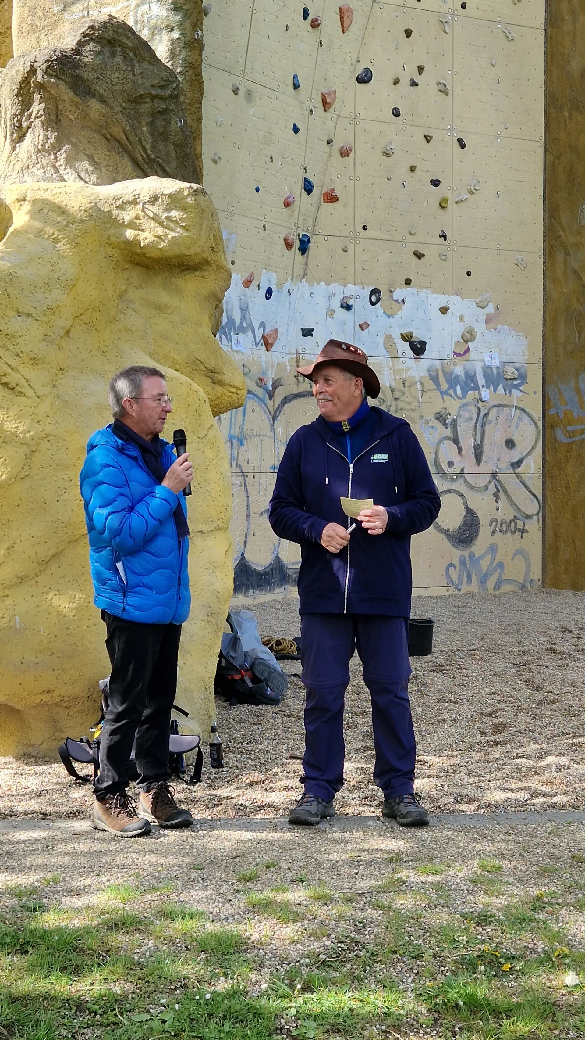 2 Menschen vor einem Kletterturm halten eine Rede | © DAV Dortmund