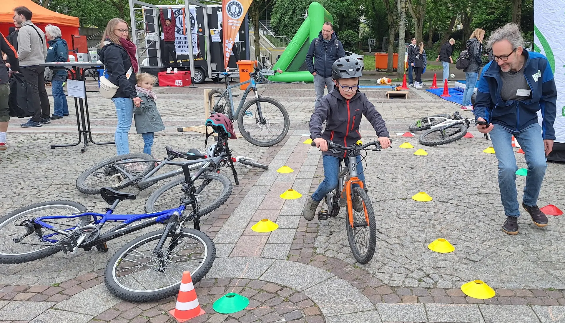 Junge Person fährt mit Fahrrad durch markierten Parcours, betreut von einer erwachsenen Person. | © DAV Dortmund