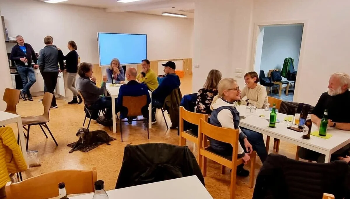 Mehrere Personen sitzen an Tischen in einem hellen Raum, unterhalten sich und trinken. | © DAV Dortmund