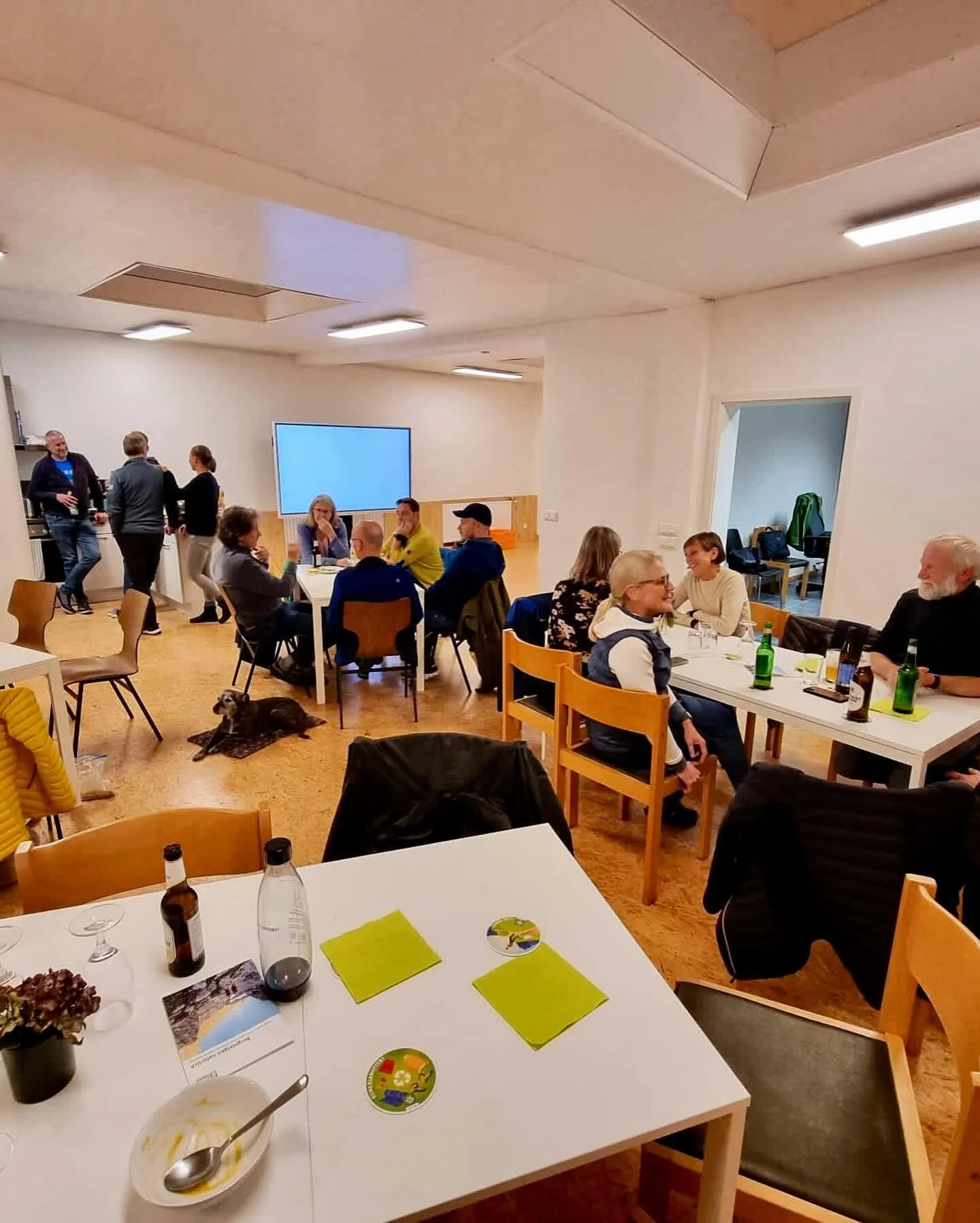 Mehrere Personen sitzen an Tischen in einem hellen Raum, unterhalten sich und trinken. | © DAV Dortmund