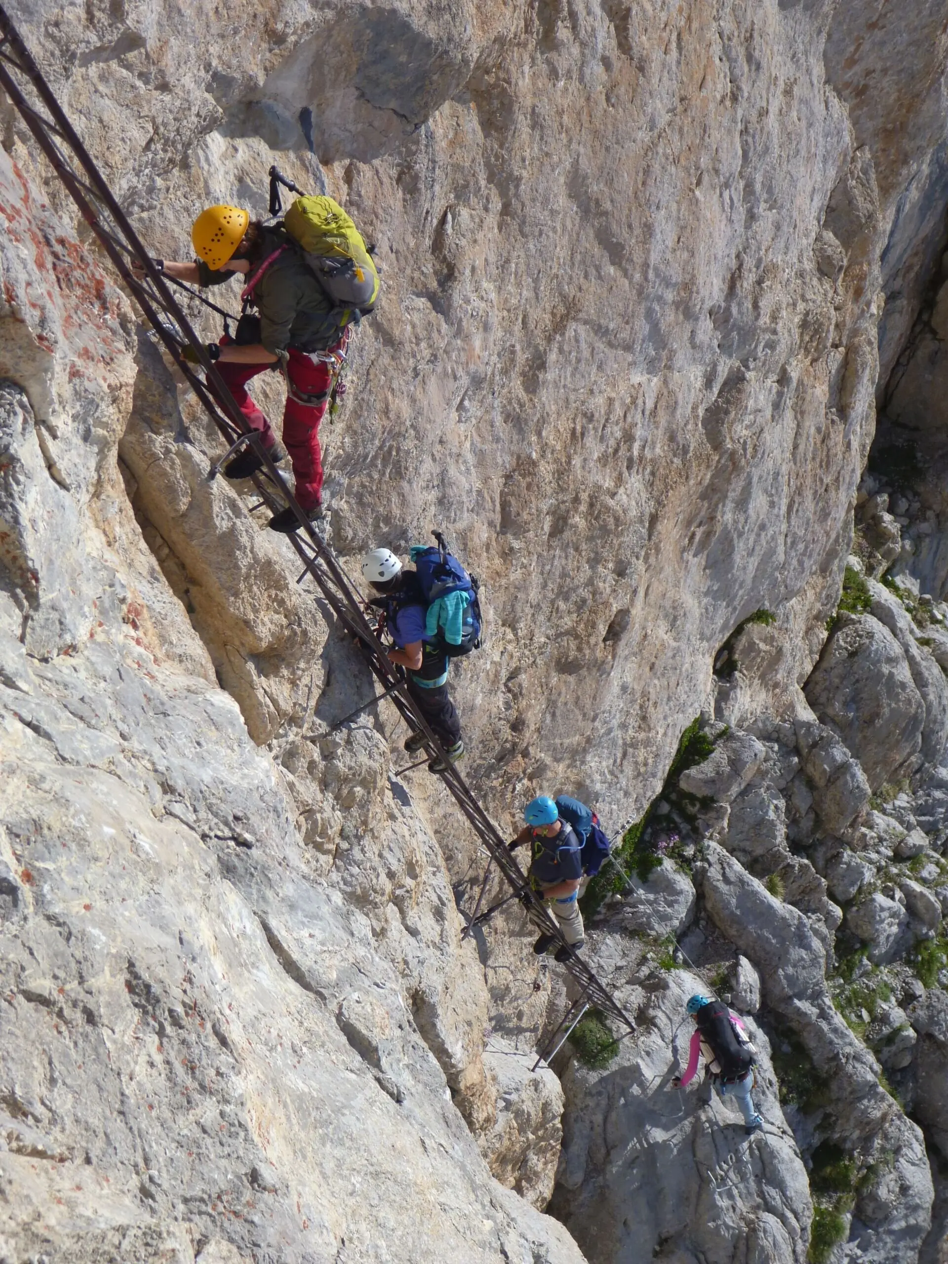 Mehrere Personen klettern mit Helm und Klettersteigset eine senkrechte Felswand hinauf. | © DAV Dortmund