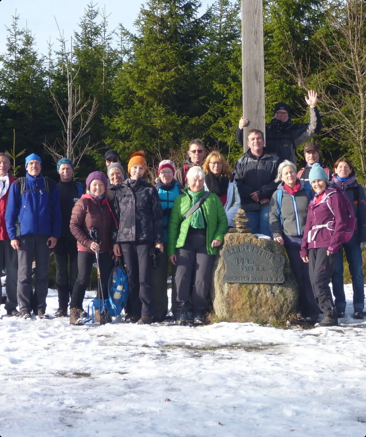 Gruppe von Wander*innen posiert bei Schnee an einem Gipfelkreuz mit Wald im Hintergrund. | © /059 - Sektion Dortmund/kletteranlagen/sektionszentrum