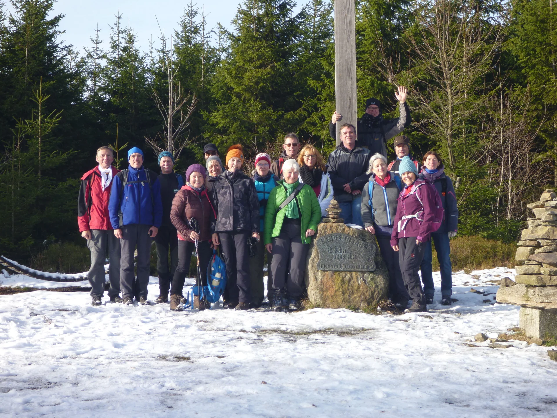 Gruppe von Wander*innen posiert bei Schnee an einem Gipfelkreuz mit Wald im Hintergrund. | © /059 - Sektion Dortmund/kletteranlagen/sektionszentrum