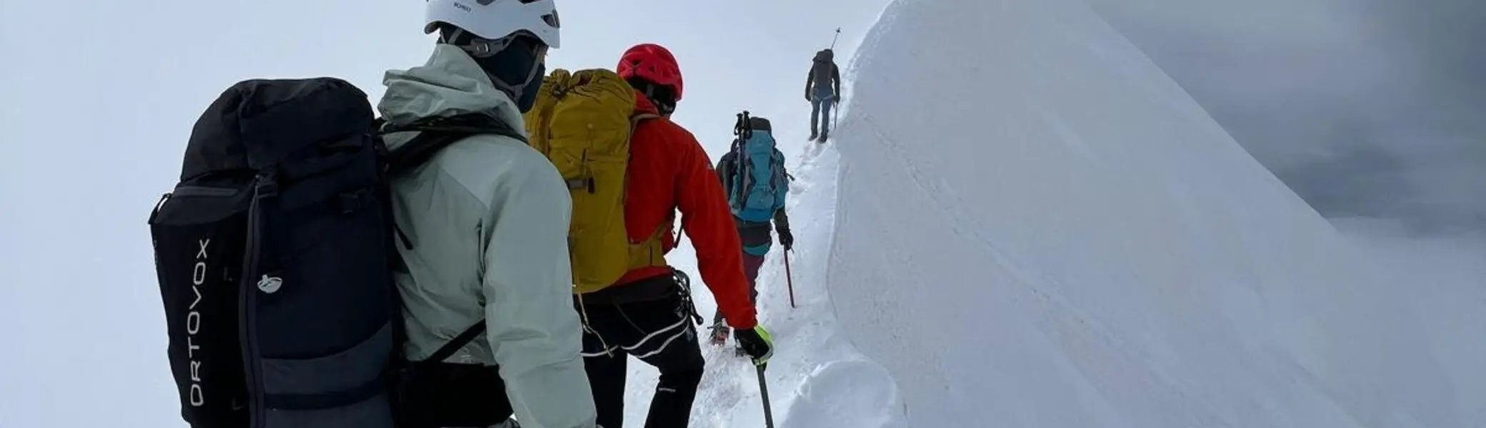Eine Gruppe Bergsteiger*innen steigt mit Steigeisen und Pickel einen schmalen Schneekamm hinauf. | © DAV Dortmund