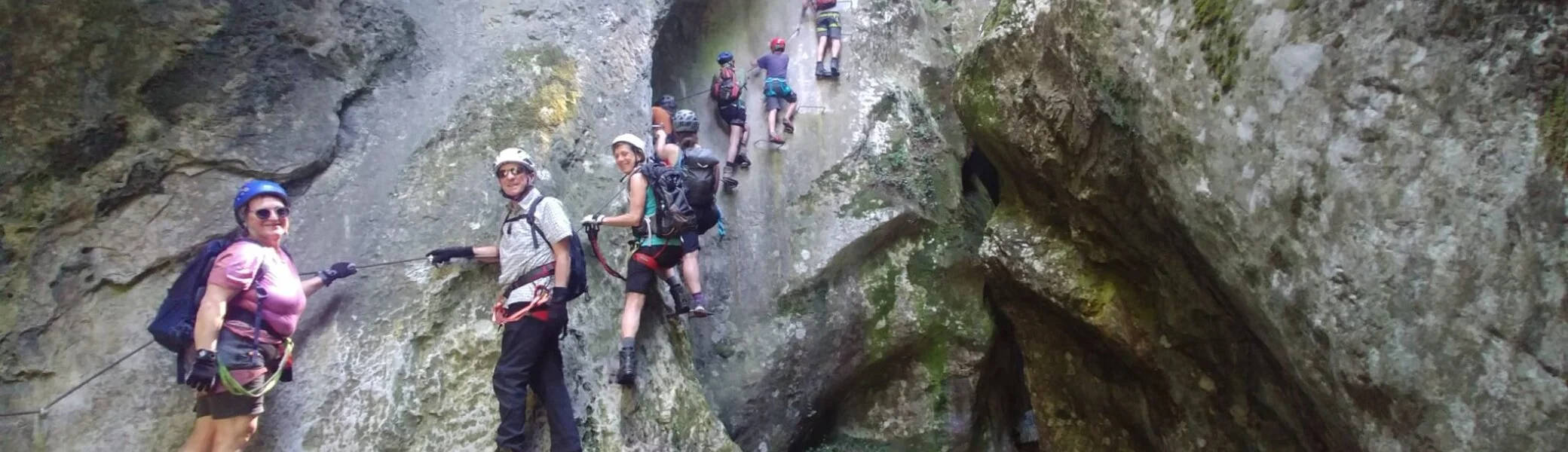 Wandergruppe in Klettersteigausrüstung durchquert eine enge Felsschlucht. | © DAV Dortmund