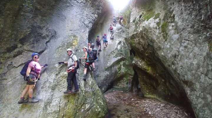 Wandergruppe in Klettersteigausrüstung durchquert eine enge Felsschlucht. | © DAV Dortmund