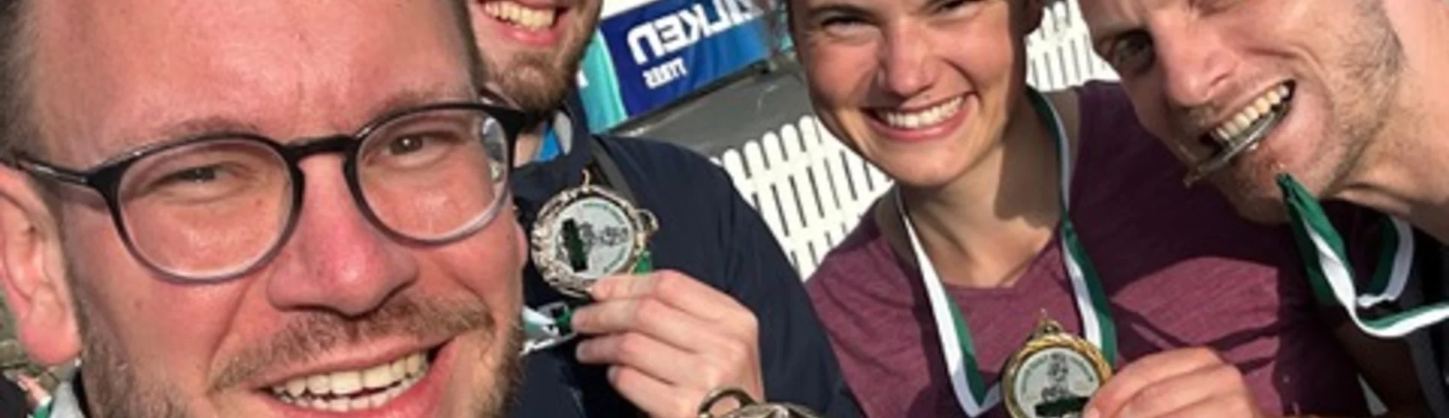 Vier Teilnehmende eines Sportevents zeigen ihre Medaillen und lachen in die Kamera. | © Jens Neuhäuser