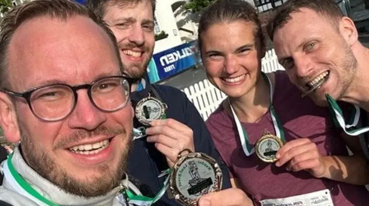 Vier Teilnehmende eines Sportevents zeigen ihre Medaillen und lachen in die Kamera. | © Jens Neuhäuser