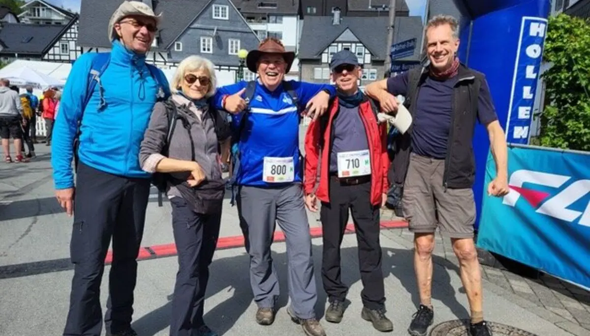 Fünf Personen stehen lächelnd mit Startnummern unter einem Zieleinlaufbogen bei einem Wanderwettbewerb. | © Klaus Dieter Schüler