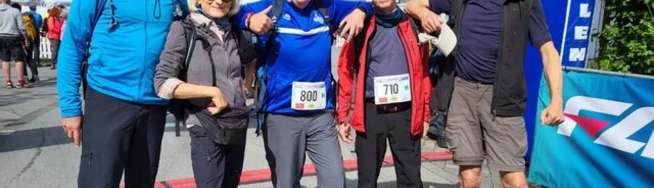 Fünf Personen stehen lächelnd mit Startnummern unter einem Zieleinlaufbogen bei einem Wanderwettbewerb. | © Klaus Dieter Schüler