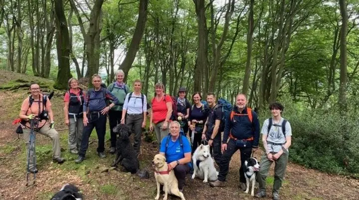 Eine große Wandergruppe mit mehreren Hunden steht im grünen Wald für ein Gruppenfoto. | © Klaus Dieter Schüler