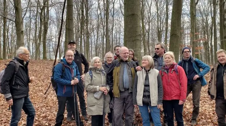 Ältere Wandergruppe steht lachend im Laubwald zwischen hohen Bäumen. | © DAV Dortmund