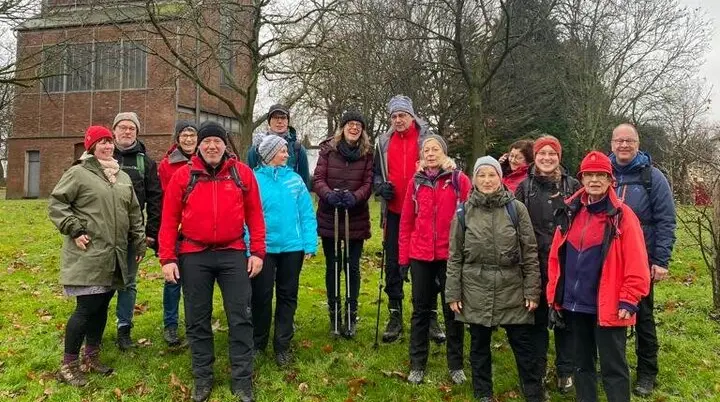Gruppe von Wander*innen steht auf einer Wiese vor einem alten Wasserturm bei grauem Wetter. | © DAV Dortmund