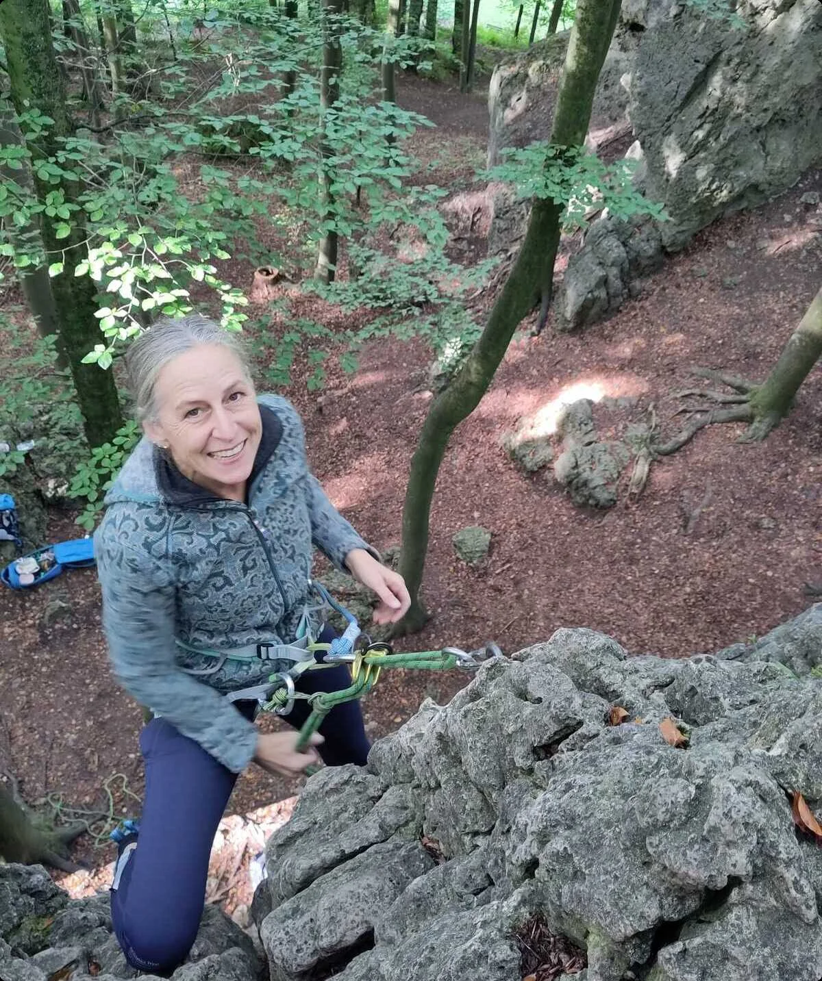 Eine Frau sichert sich beim Klettern an einem Felsen im Wald. | © DAV Dortmund
