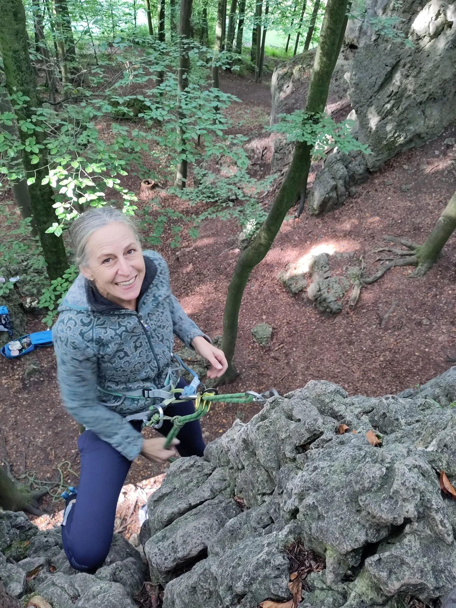 Eine Frau sichert sich beim Klettern an einem Felsen im Wald. | © DAV Dortmund