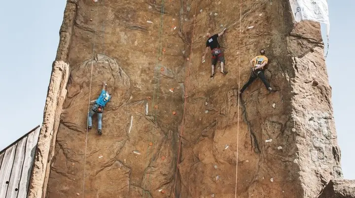 An einem Kletterturm wird geklettert. Zuschauer stehen am Boden | © DAV Dortmund