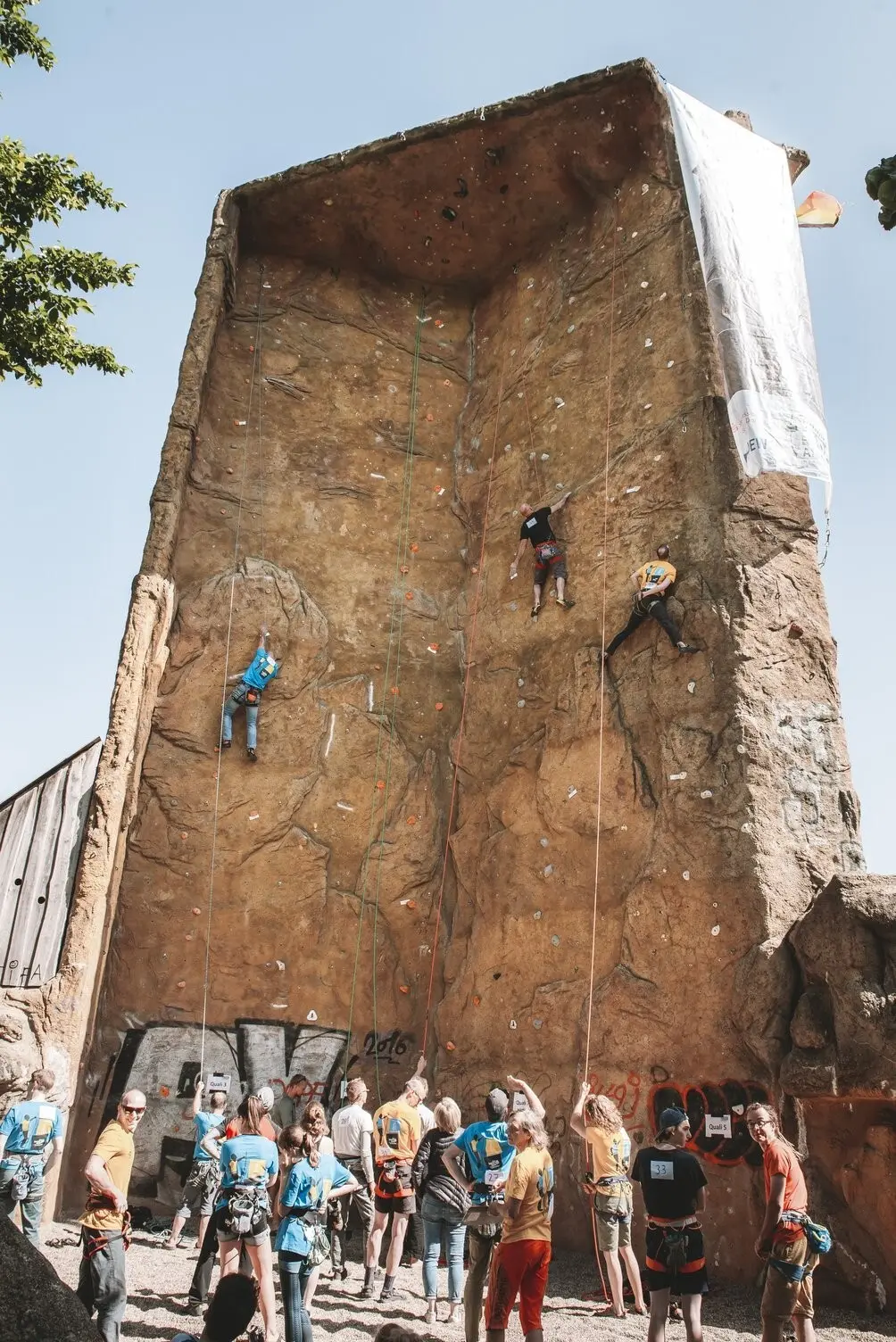An einem Kletterturm wird geklettert. Zuschauer stehen am Boden | © DAV Dortmund