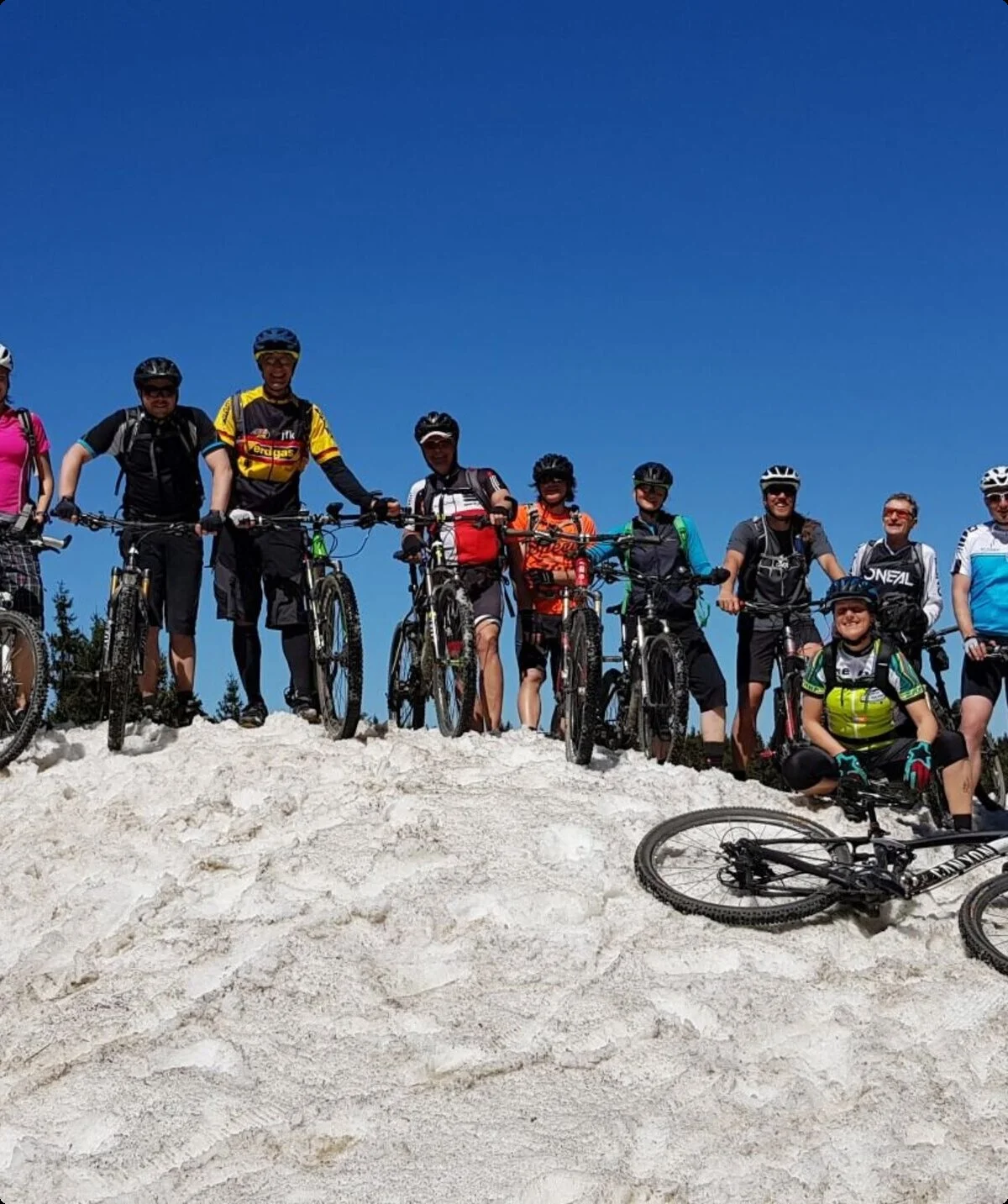 Gruppe von Mountainbiker*innen posiert auf einem verschneiten Hügel mit blauem Himmel. | © DAV Dortmund