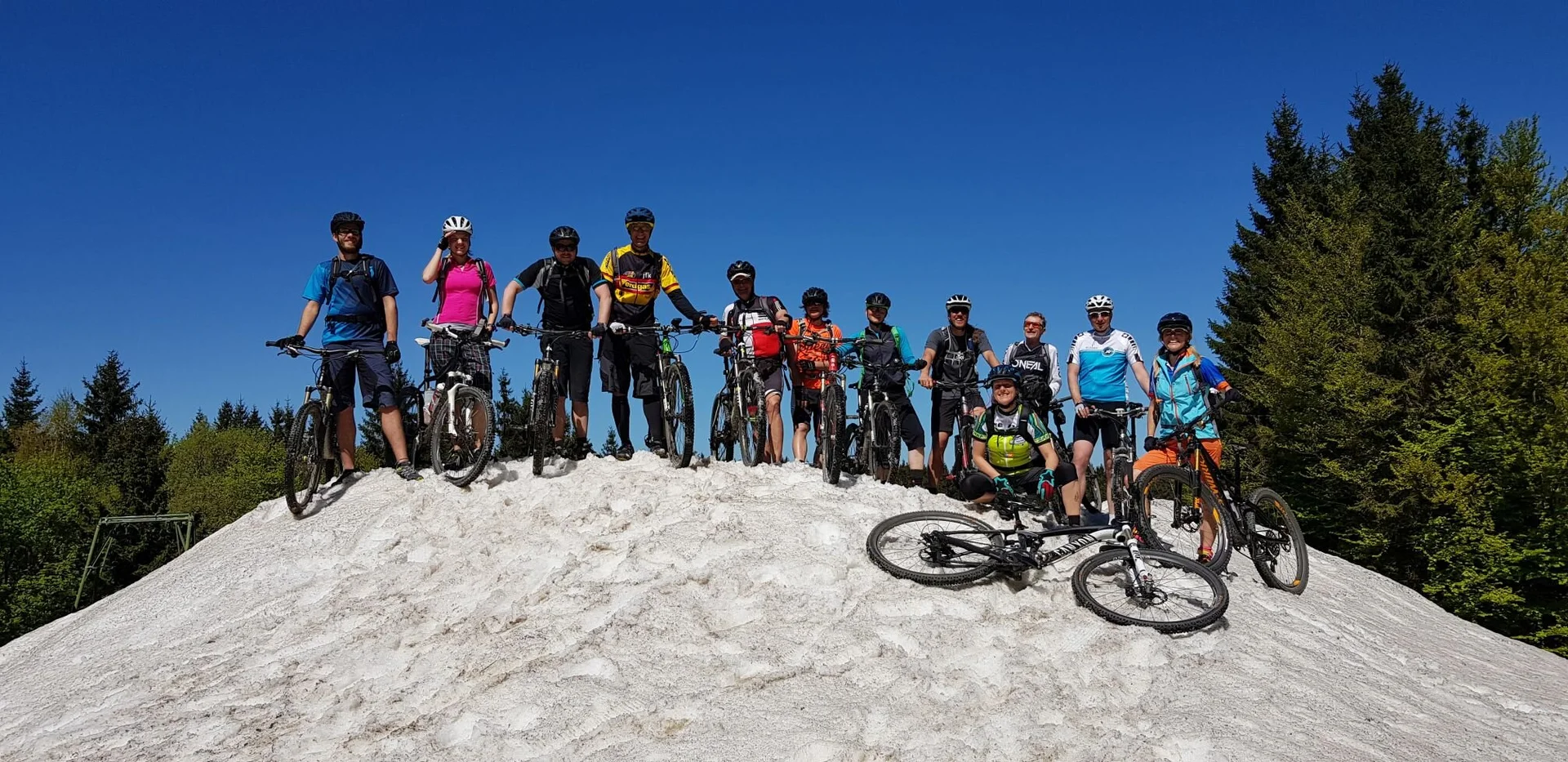 Gruppe von Mountainbiker*innen posiert auf einem verschneiten Hügel mit blauem Himmel. | © DAV Dortmund