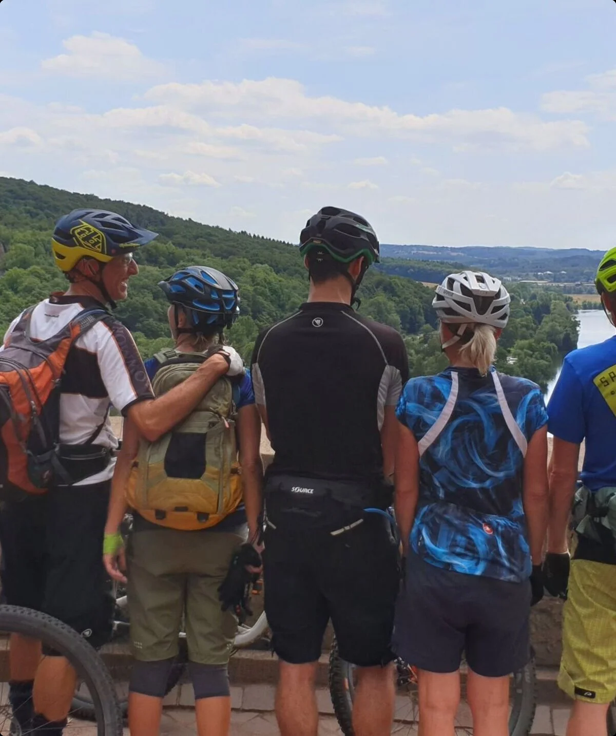 Mountainbike-Gruppe steht an einer Mauer mit Blick ins grüne Tal. | © DAV Dortmund