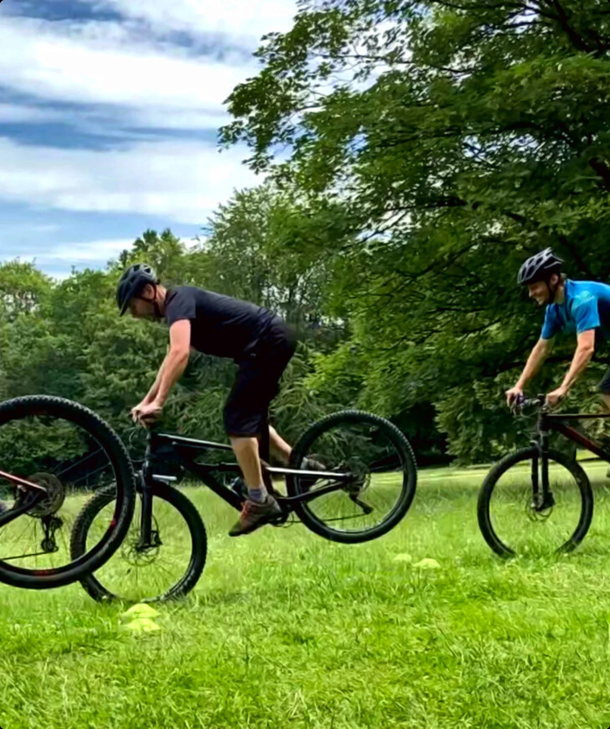 Vier Personen üben gleichzeitig eine Mountainbike-Technik auf einer Wiese mit Bäumen im Hintergrund. | © DAV Dortmund