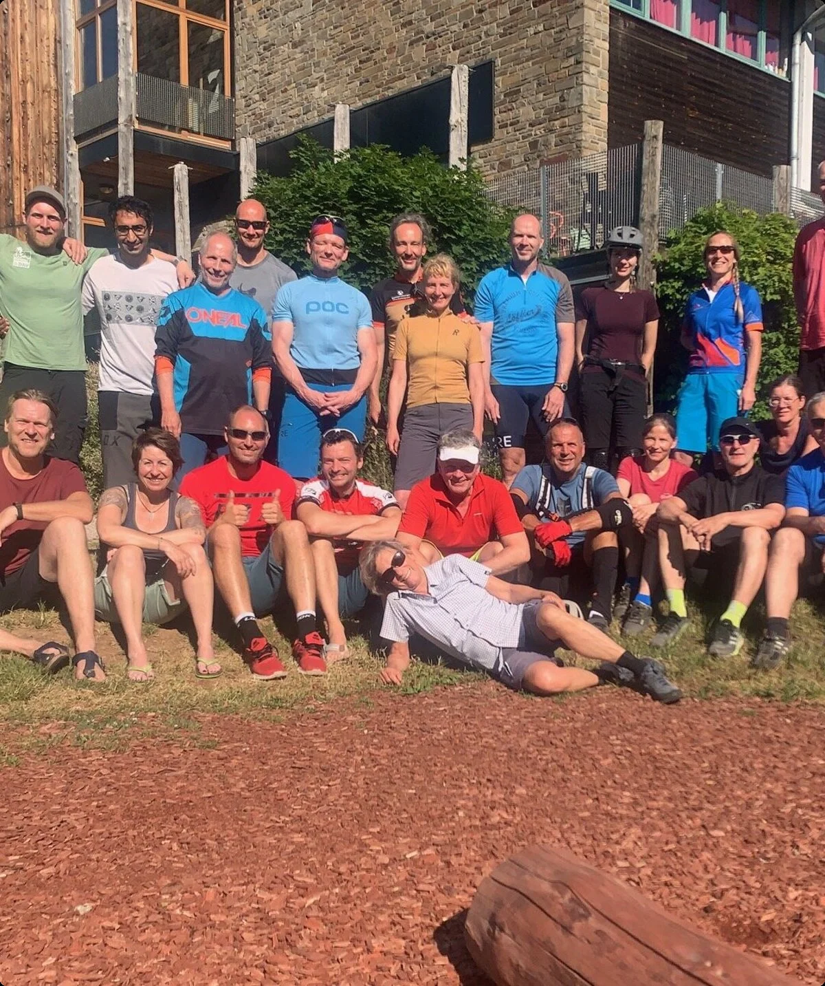 Gruppe von Mountainbiker*innen posiert fröhlich vor einer Unterkunft bei sonnigem Wetter. | © DAV Dortmund