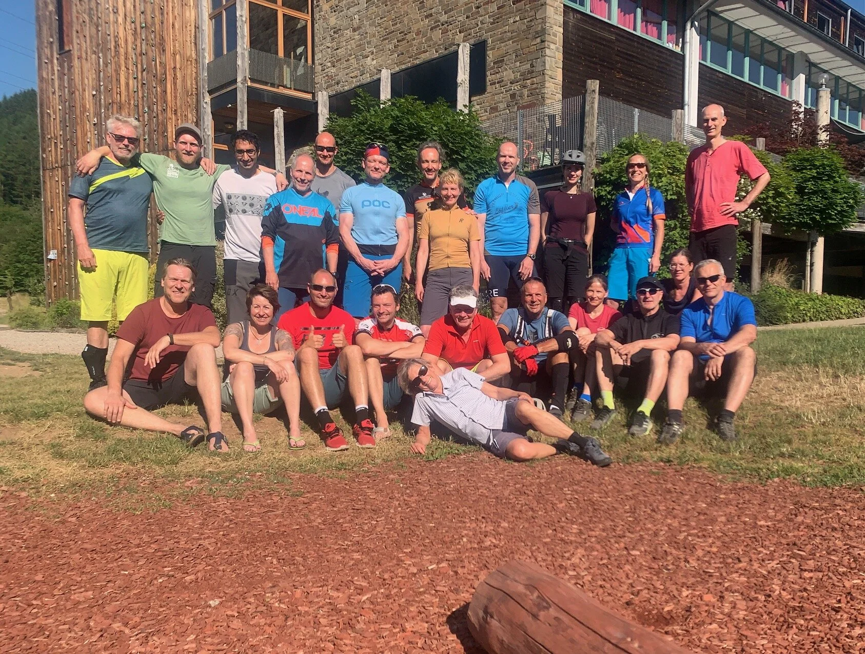 Gruppe von Mountainbiker*innen posiert fröhlich vor einer Unterkunft bei sonnigem Wetter. | © DAV Dortmund