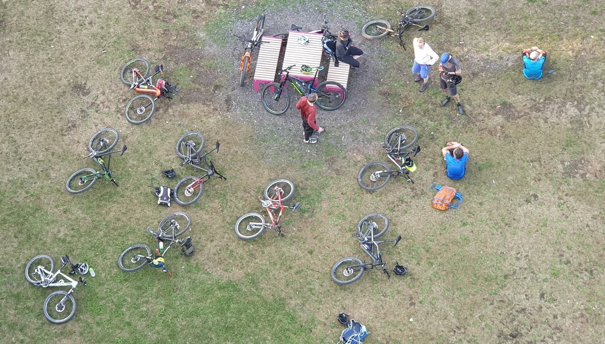 Luftaufnahme einer Gruppe von Mountainbiker*innen bei einer Rast mit abgestellten Fahrrädern im Kreis. | © DAV Dortmund