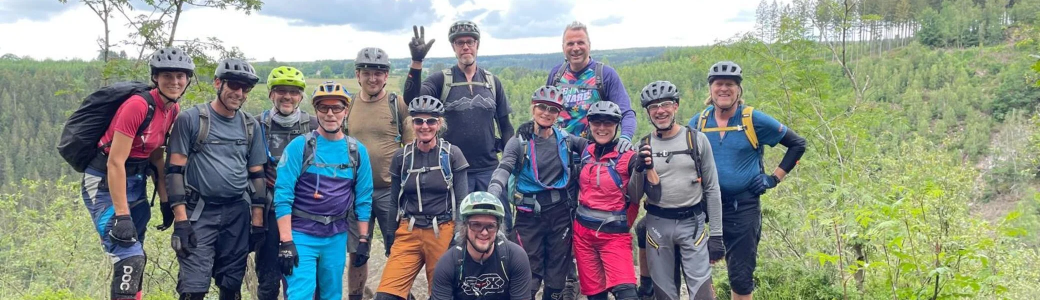 Eine große Gruppe von Mountainbiker*innen posiert gemeinsam auf einem Felsen mit Ausblick. | © DAV Dortmund